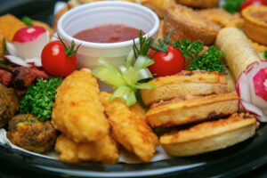 Spring rolls, mini-quiches, chicken goujons on a plate with dipping sauce