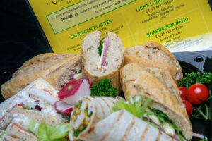 Plate of sandwiches and wraps with a yellow leaflet in the background
